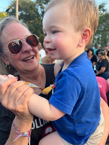 A grandma and her toddler grandson dance at a festival outdoors.