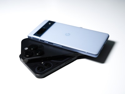 The blue Pixel 7a sitting on some iPhones.