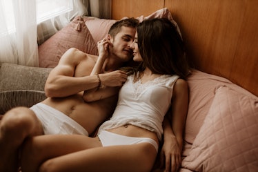 A man and woman in their underwear in bed, about to kiss.