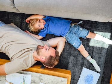 A child and dad lying on the floor, talking.