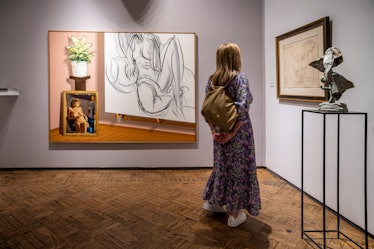 a woman eyeing a painting in an art fair booth