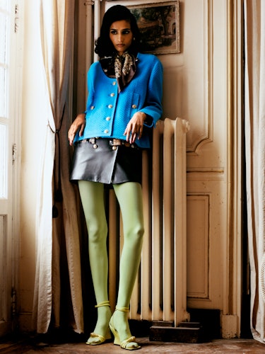 Prency Dedha wears a blue jacket, skirt, silk scarf, and yellow shoes; vintage shirt, earrings and g...