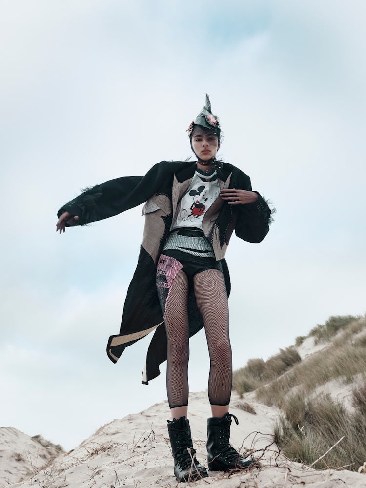 Model wears a mickey mouse t-shirt, coat, fishnet tights, combat boots, and gloves.