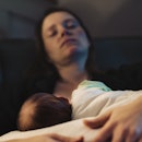 A mom closing her eyes on the couch while breastfeeding her newborn.