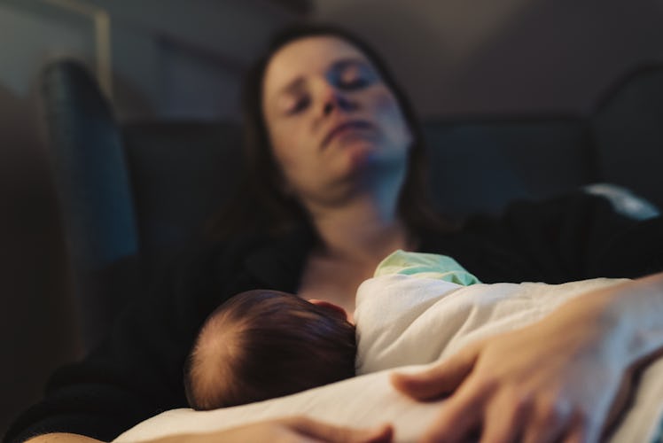 A mom closing her eyes on the couch while breastfeeding her newborn.