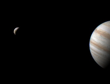 Jupiter and its bands of clouds appear on the right, and a crescent Io shows up on the left. They ar...