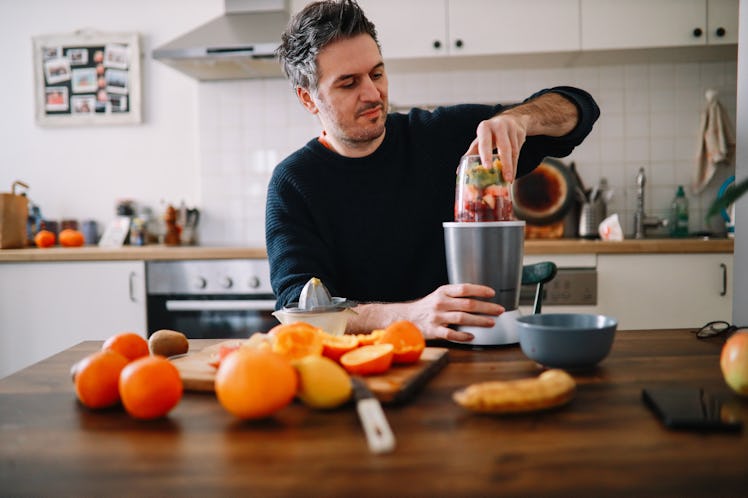 A man making a fruit smoothie in his kitchen.