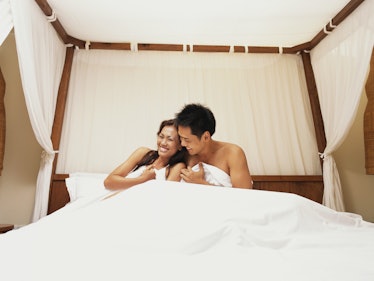 Couple in their 30s in bed cuddling and laughing