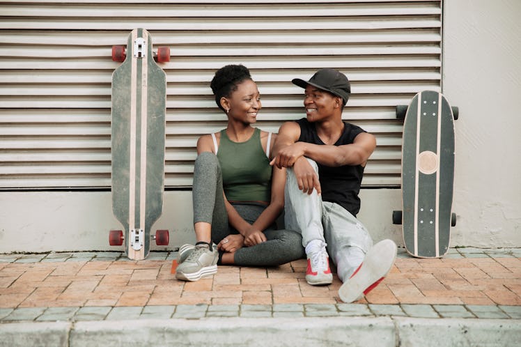 Young Gemini couple looking in love after skateboarding.