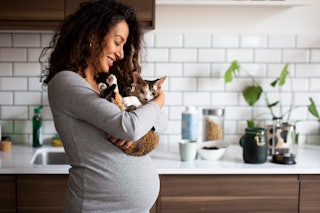 A pregnant woman holds her cat.