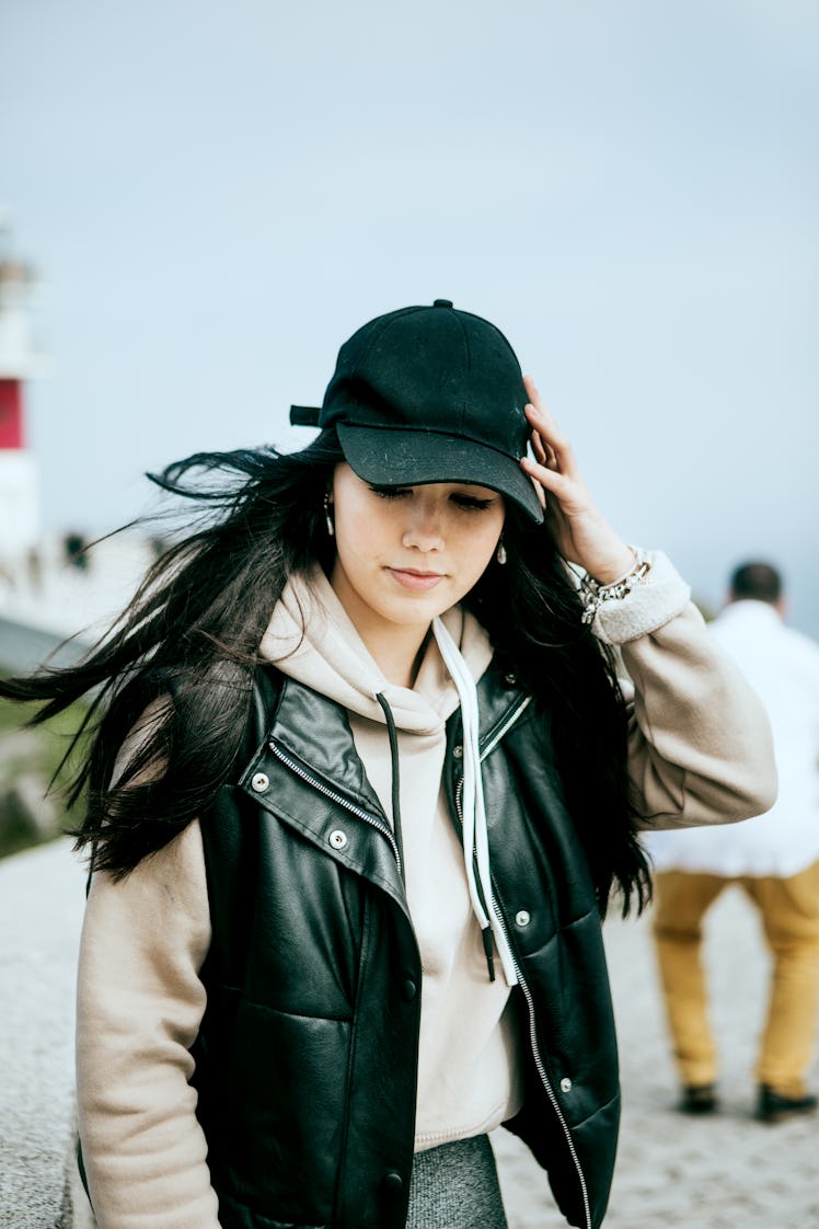 Young woman holding her hat during one of June 2023's planetary retrogrades.