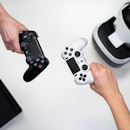 Two people holding Sony DualShock controllers and virtual reality headset