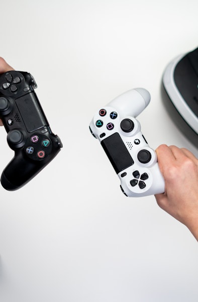 Two people holding Sony DualShock controllers and virtual reality headset