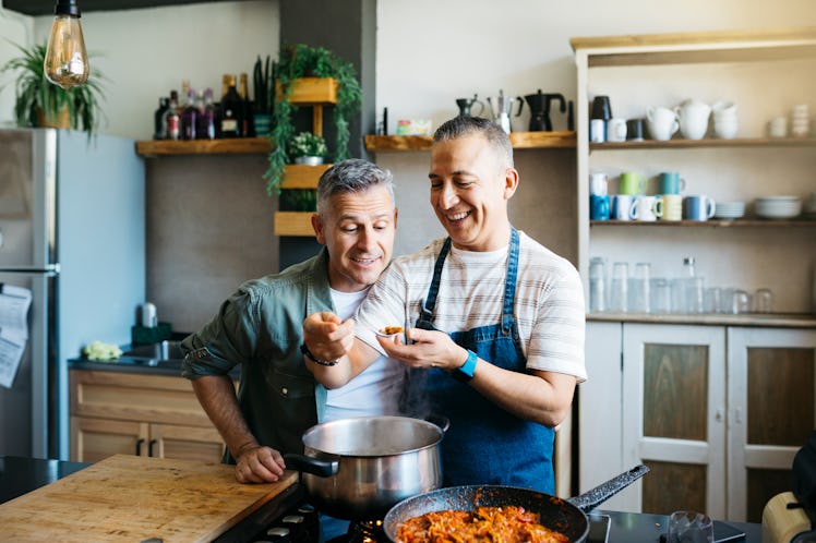 Two happy gay men cooking dinner together