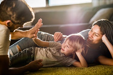 Dad high-fiving child on floor as mom looks on happily