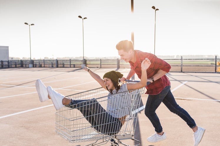 Happy, playful man pushing happy woman around in a shopping cart