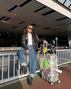 woman wearing a bright red lip and holding luggage at an airport