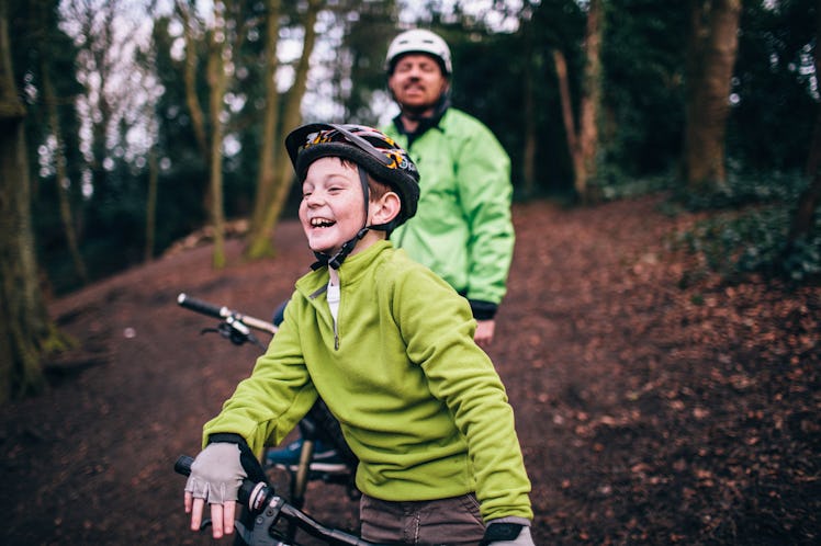 A boy and his dad mountain biking in the woods.