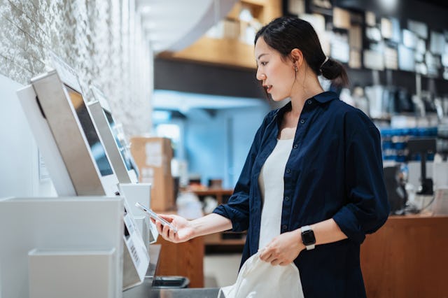 A woman looks at the payment screen at a self-checkout kiosk.