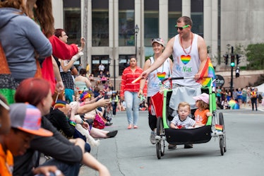 A man hands out items to the crowd that has gathered for the Halifax Pride Parade. Man pushes a stro...