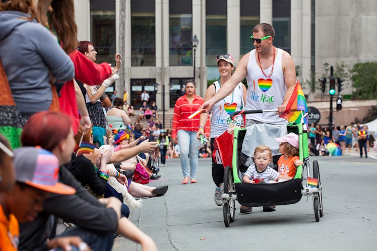A man hands out items to the crowd that has gathered for the Halifax Pride Parade. Man pushes a stro...
