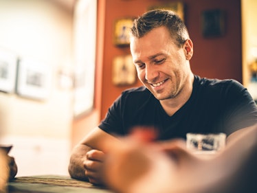 Calm man looking downwards and smiling while sitting at a table