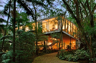 a modern looking house shrouded behind trees in sao paulo, brazil