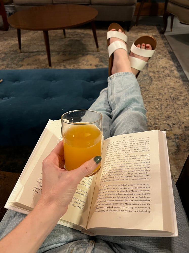 The author's feet up on an ottoman wearing the Reef Cushion Vista slides, the best summer sandals fo...