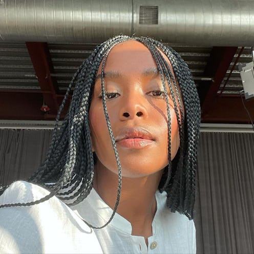 Beautiful Black woman with braids and glowing skin posing for a selfie in a white shirt