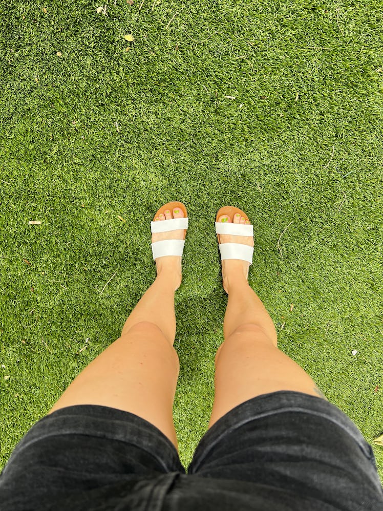 The author wears the Reef Cushion Vista slides, the best summer sandals for women, while standing on...