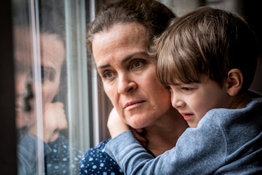 A depressed mother staring out the window, holding her son.