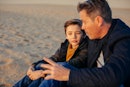 一个父亲和儿子坐在海滩上,说话。