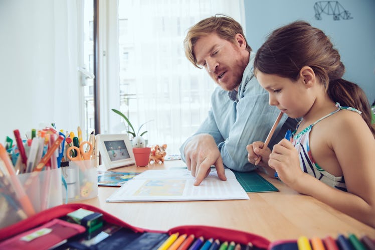 A dad doing his child's homework for them.