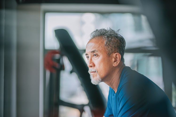 Middle aged man with grey goatee sitting contemplatively in a gym