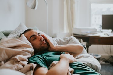 A tired man sleeping on a couch bed.