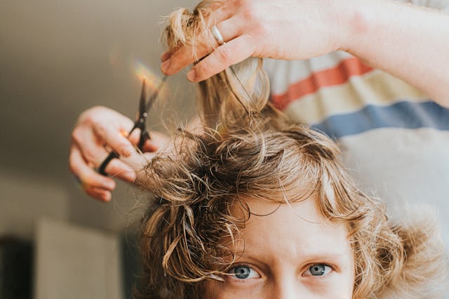 A woman cuts her child's curly hair