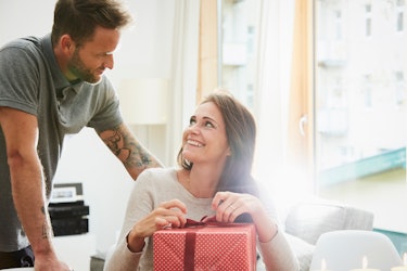 Woman about to open a gift as husband looks on