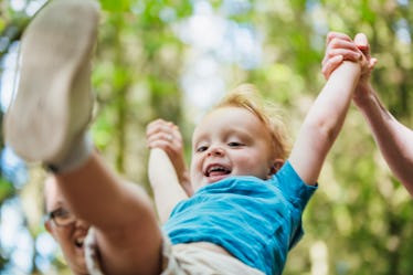 Close up of a child being swung by their arms.