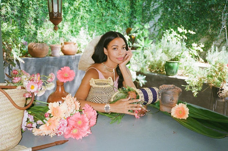 the designer Aurora James sits at a table covered in baskets and flowers