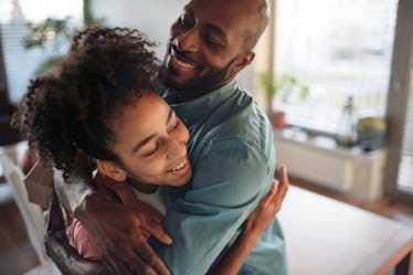 A dad and daughter hugging and smiling.