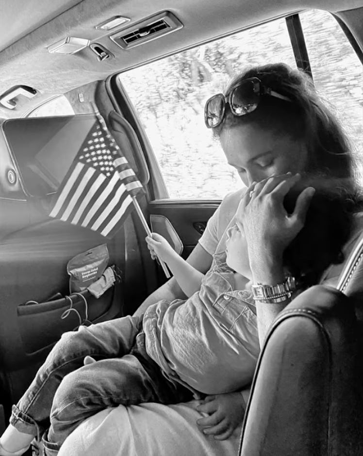 Meghan Markle and Archie ride in the back of a car. Archie carries an American flag.
