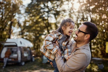 爸爸抱着他的女儿在户外在秋天,他们都笑了。