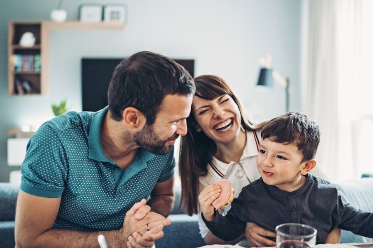 Dad and mom smiling while talking to young son at breakfast