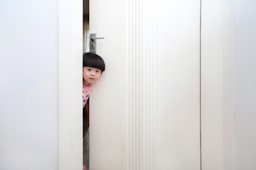 Young child peeking through crack in bedroom door