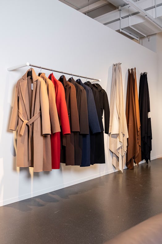 a row of neutral hued coats hanging on a rack in a museum gallery