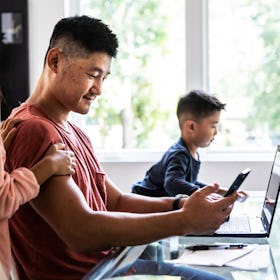 A man on his phone and laptop, ignoring his two children.