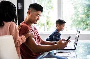 A man on his phone and laptop, ignoring his two children.