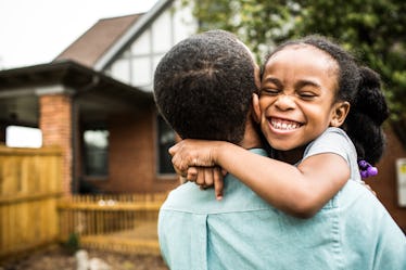 A smiling girl hugging her father.