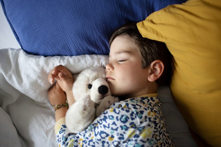 A baby sleeping with a stuffed animal in bed.