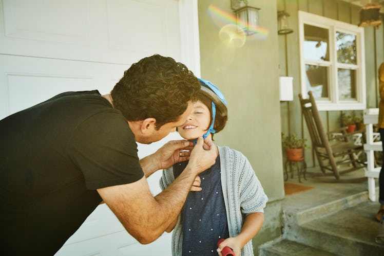 A dad straps a helmet onto his child's head.